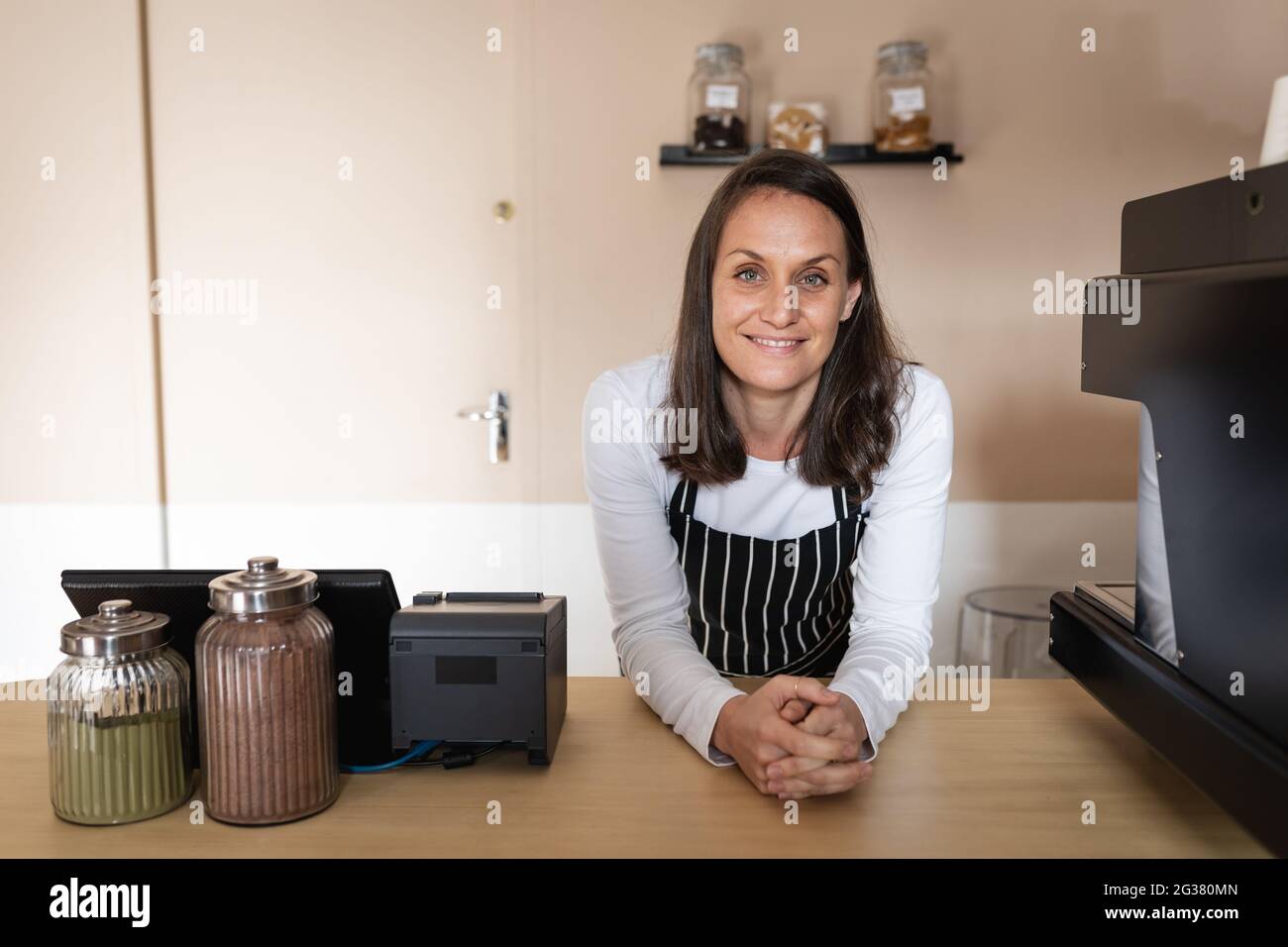 Smiling caucasian business owner standing at countertop and looking at camera Stock Photo