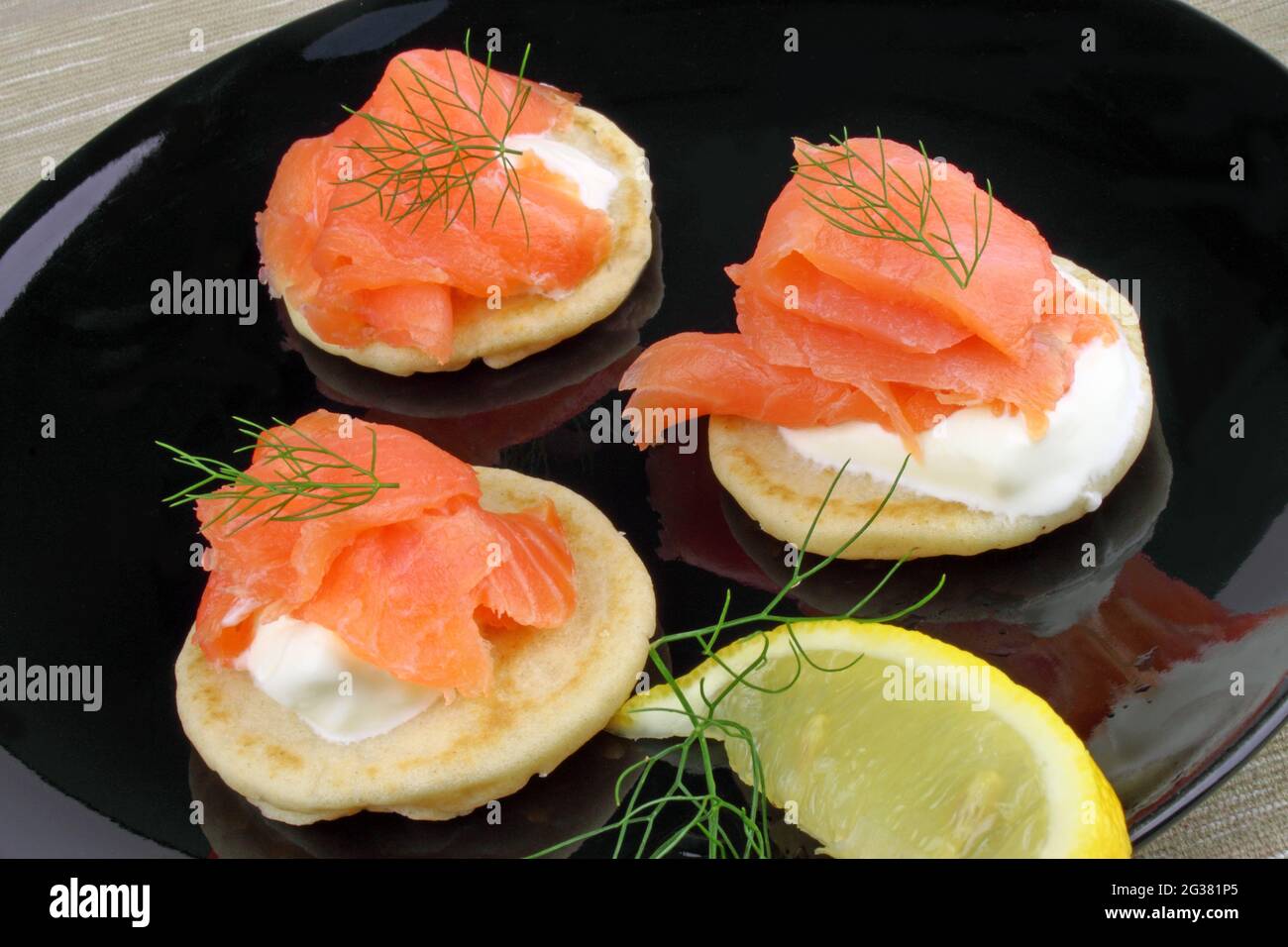 Blinis pancakes served with Crème Fraiche, Smoked Salmon and garnished with Dill. Stock Photo