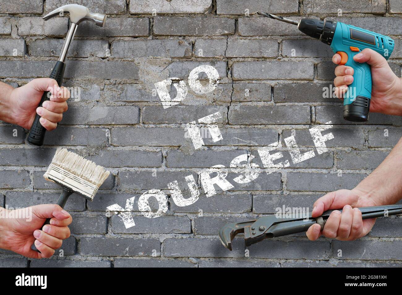 hands holding tools on grey brickwall background with writing do it yourself on it Stock Photo