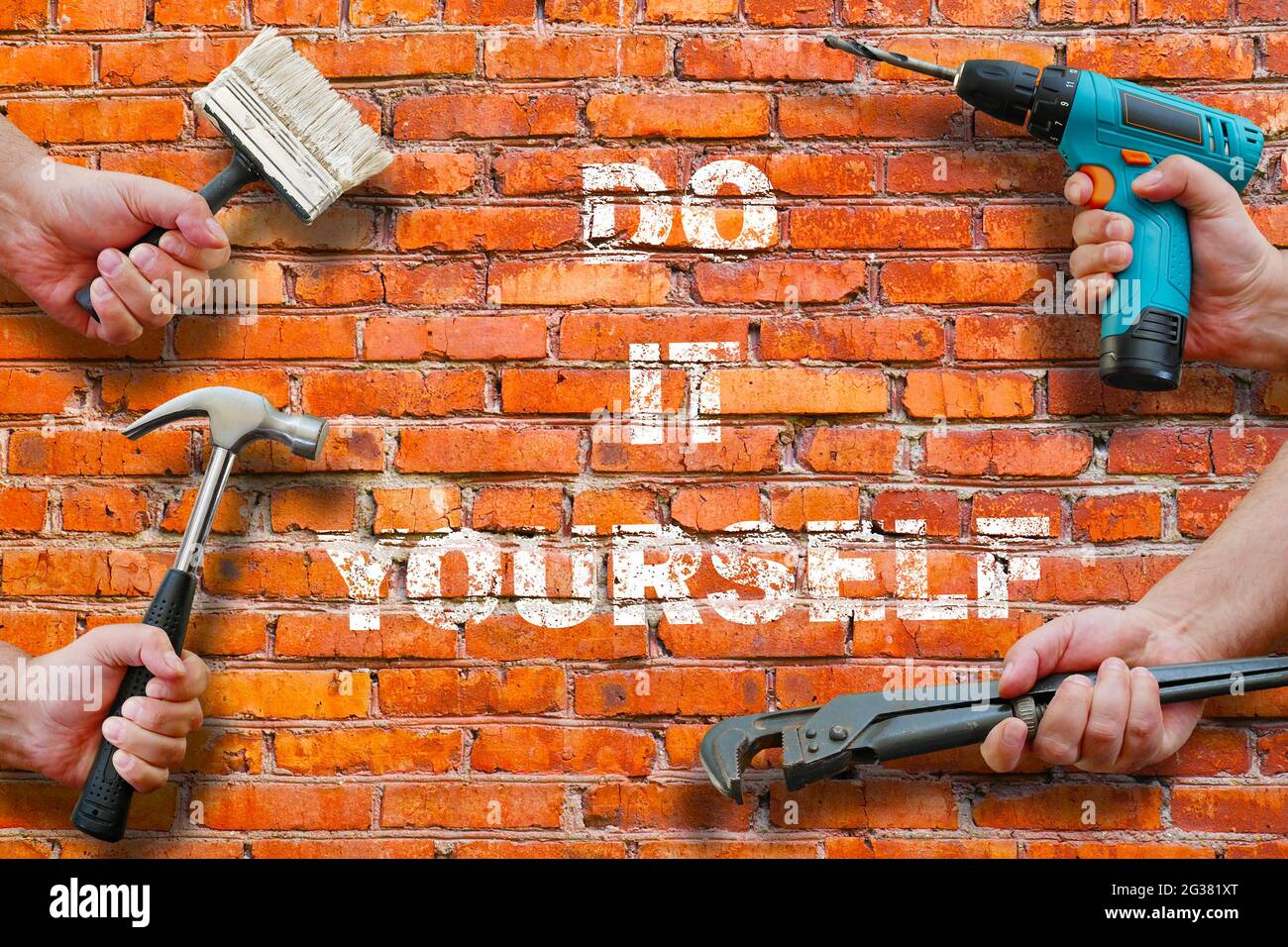 hands holding tools on brickwall background with do it yourself writing on it Stock Photo