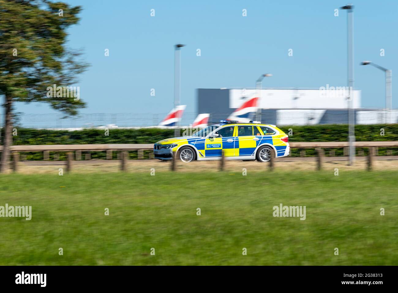 Metropolitan Police police car racing at speed with blue lights on A30 passing London Heathrow Airport, UK, on day of US President Joe Biden visit Stock Photo