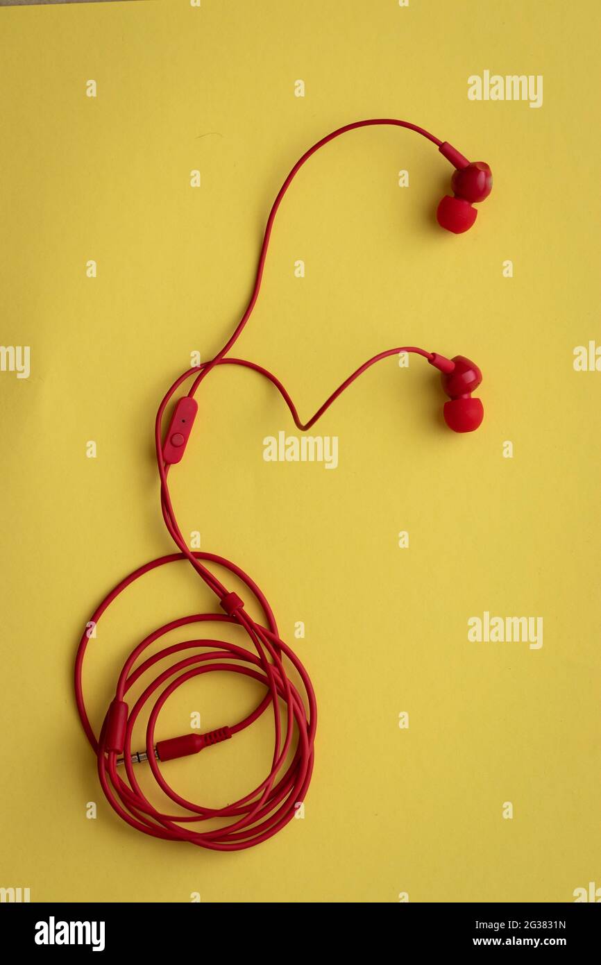 Red headphones with rolled wire, on a yellow background Stock Photo