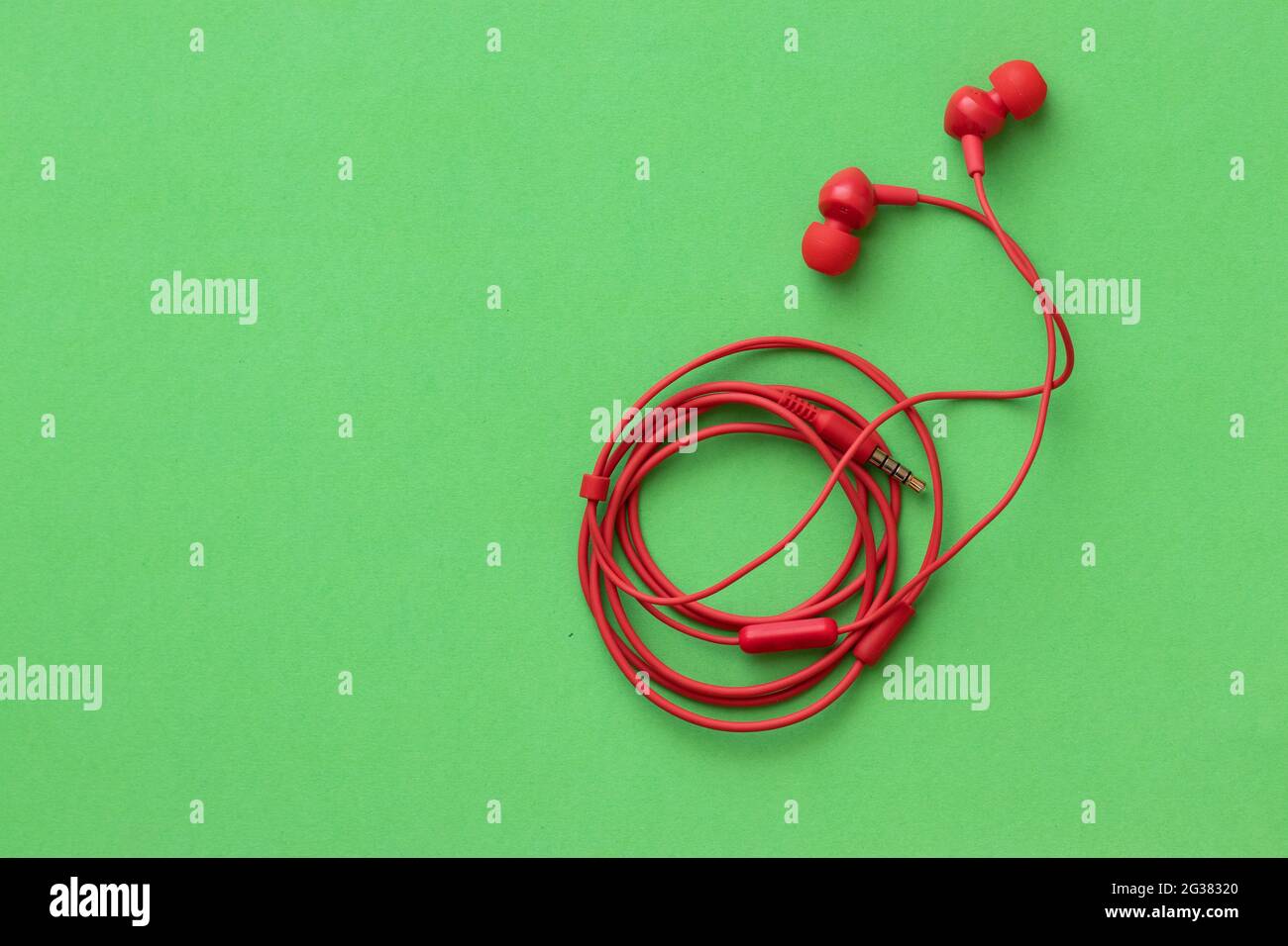 Red headphones with rolled wire, on a green background Stock Photo