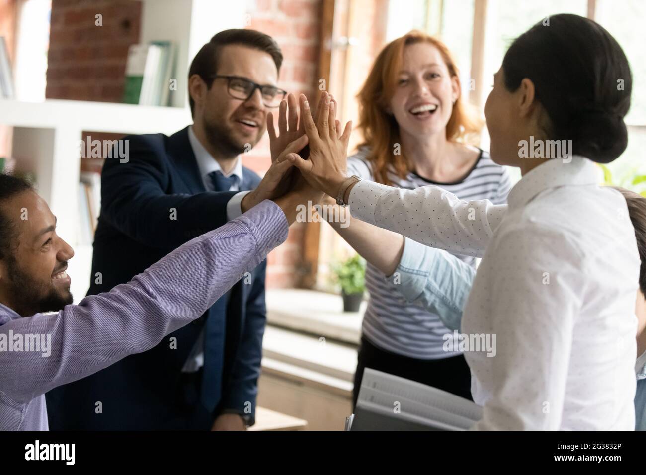 Happy successful multiracial colleagues giving high five, celebrating ...