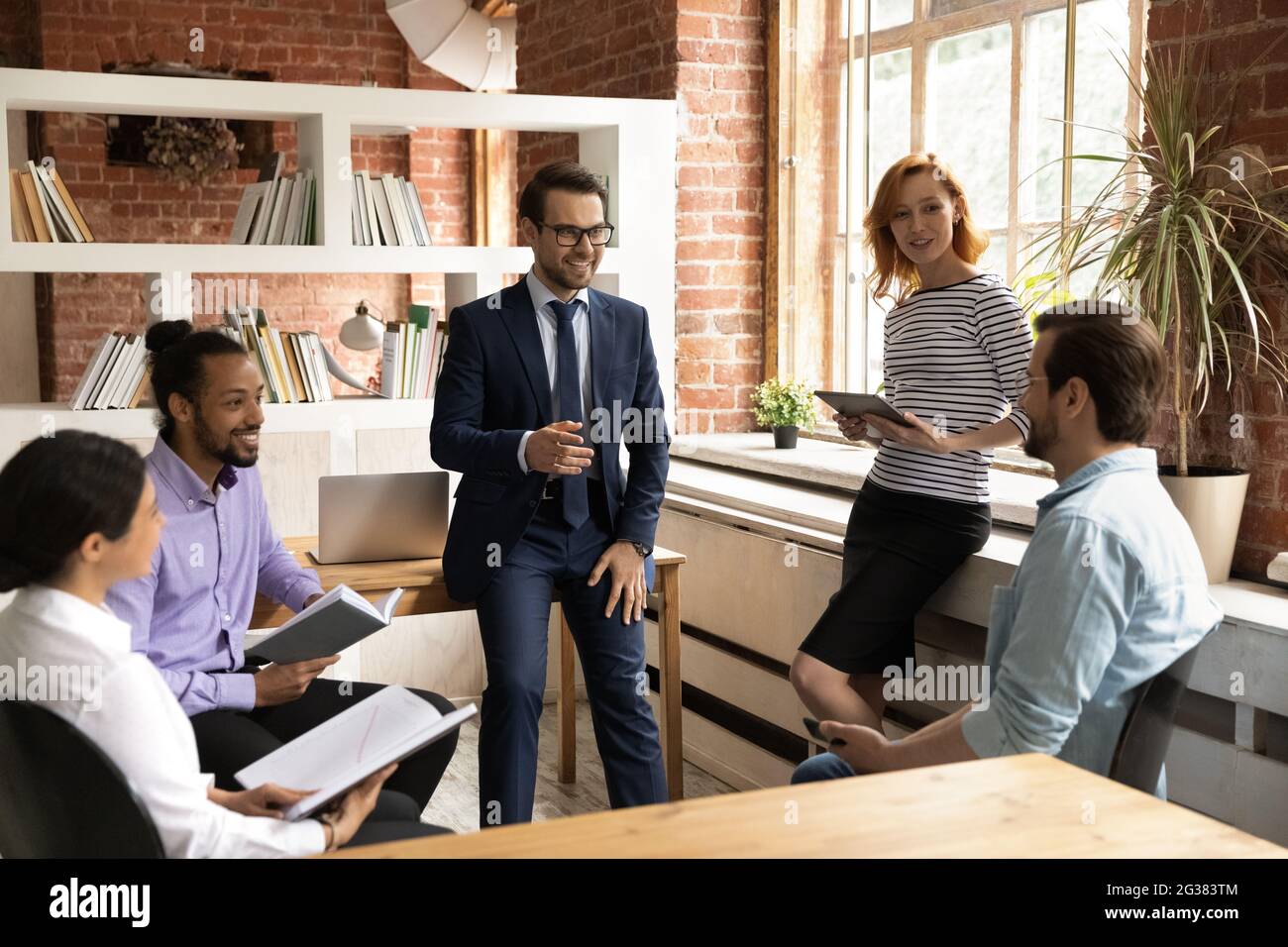 Smiling relaxed millennial diverse teammates involved in friendly conversation. Stock Photo
