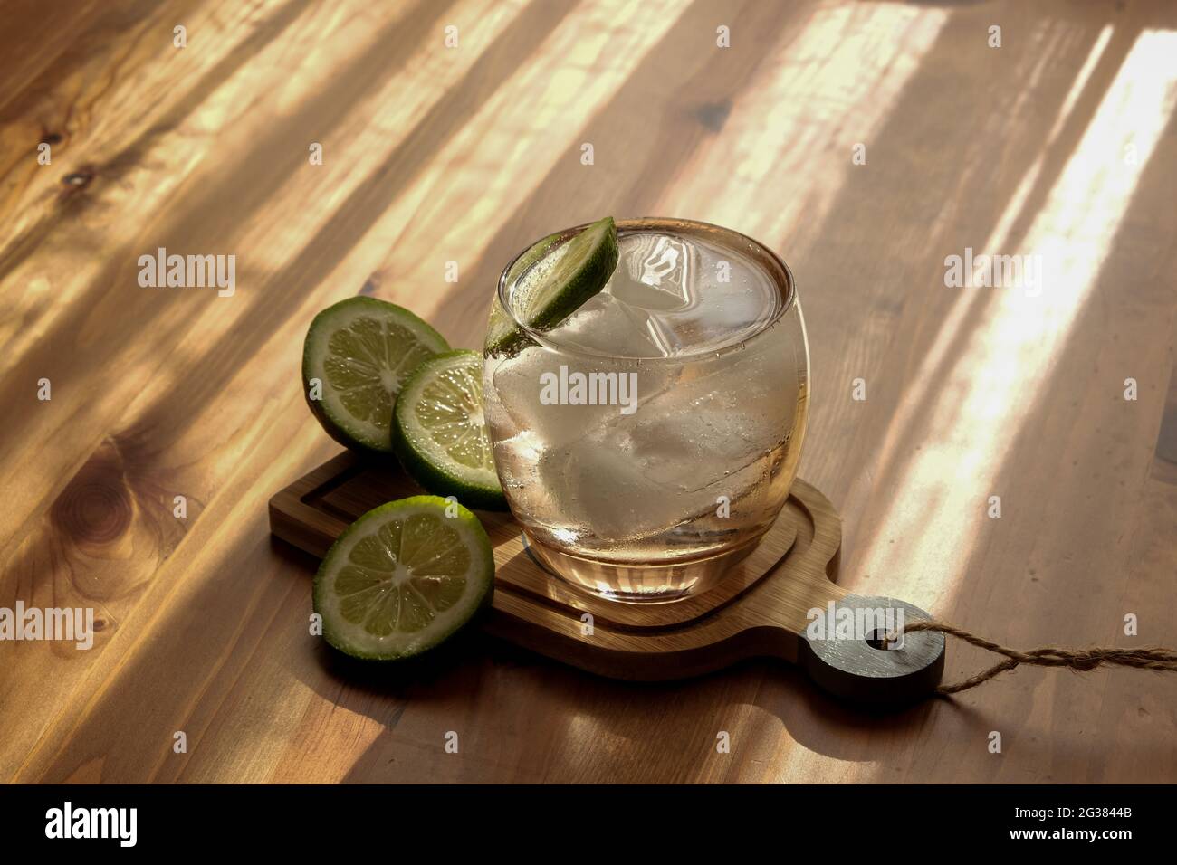 Light filtering on the table hits the soda in the glass with ice lemon. Stock Photo