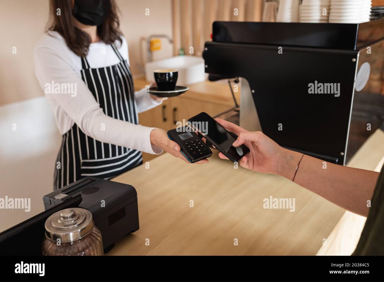 Midsection of caucasian customer paying by smartphone to caucasian female business owner Stock Photo