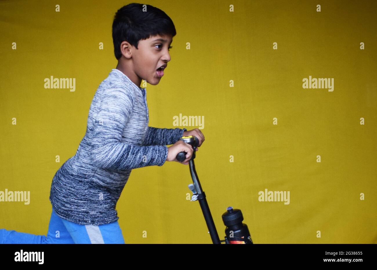 Indian little boy riding on a scooter on a yellow background Stock ...