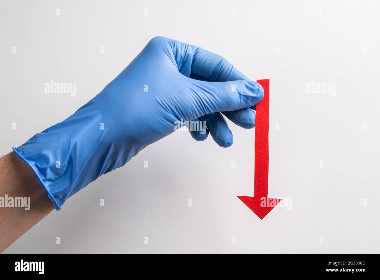 Hand in glove holding a red paper arrow pointing down on white ...