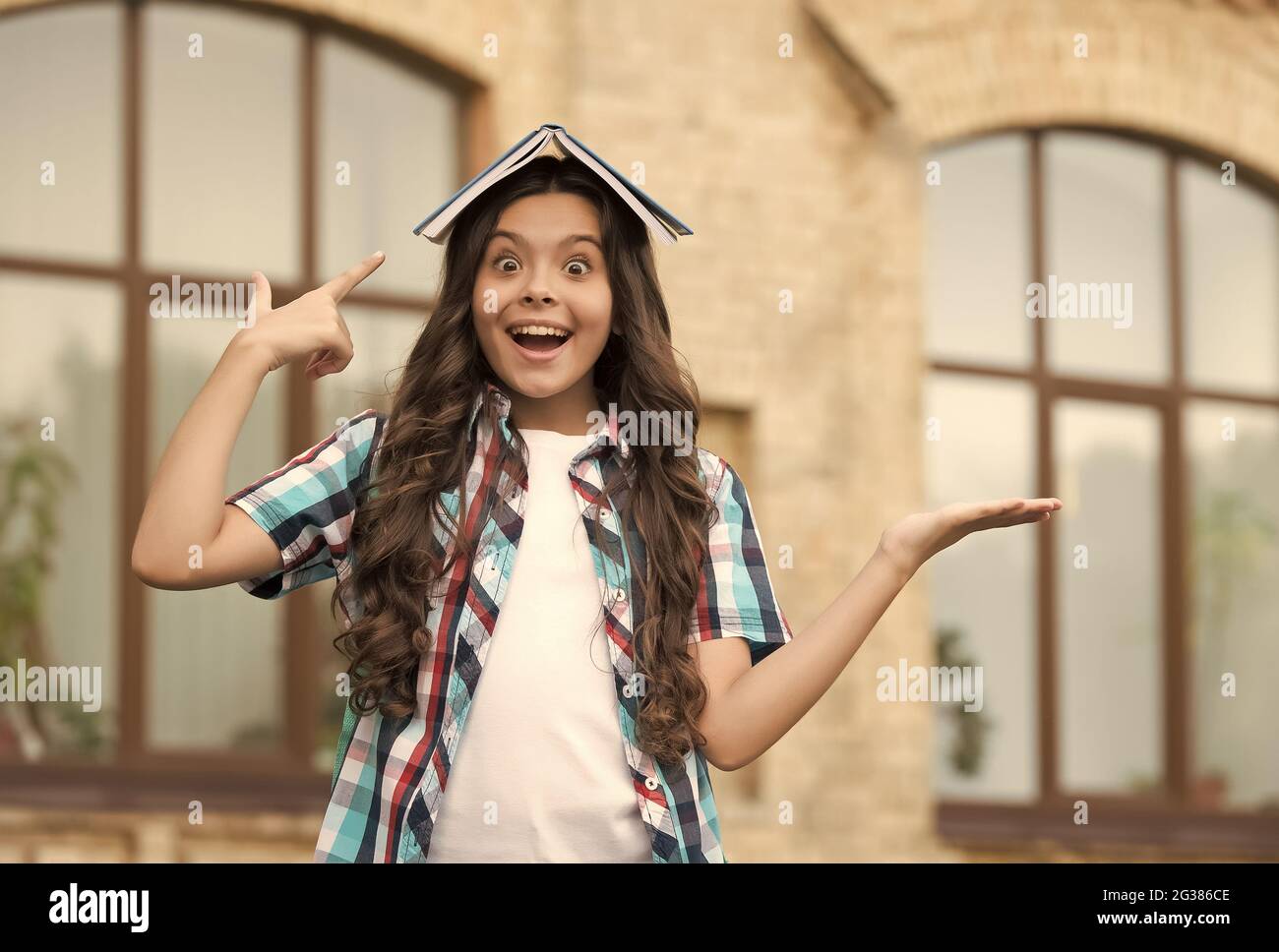 Bestselling product. Happy kid hold open hand pointing at book on head ...