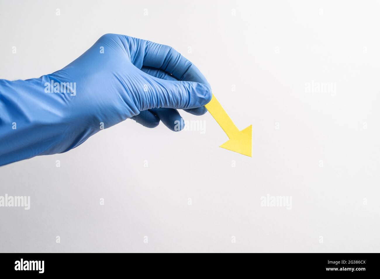 Hand in glove holding a yellow paper arrow pointing down to the right ...