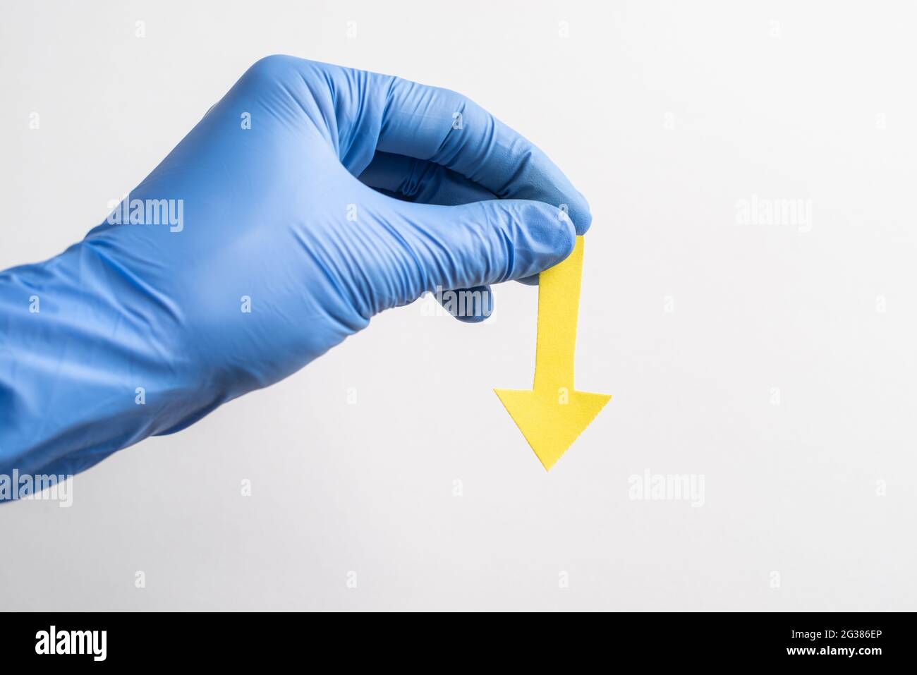 Hand in glove holding a yellow paper arrow pointing down Stock Photo ...