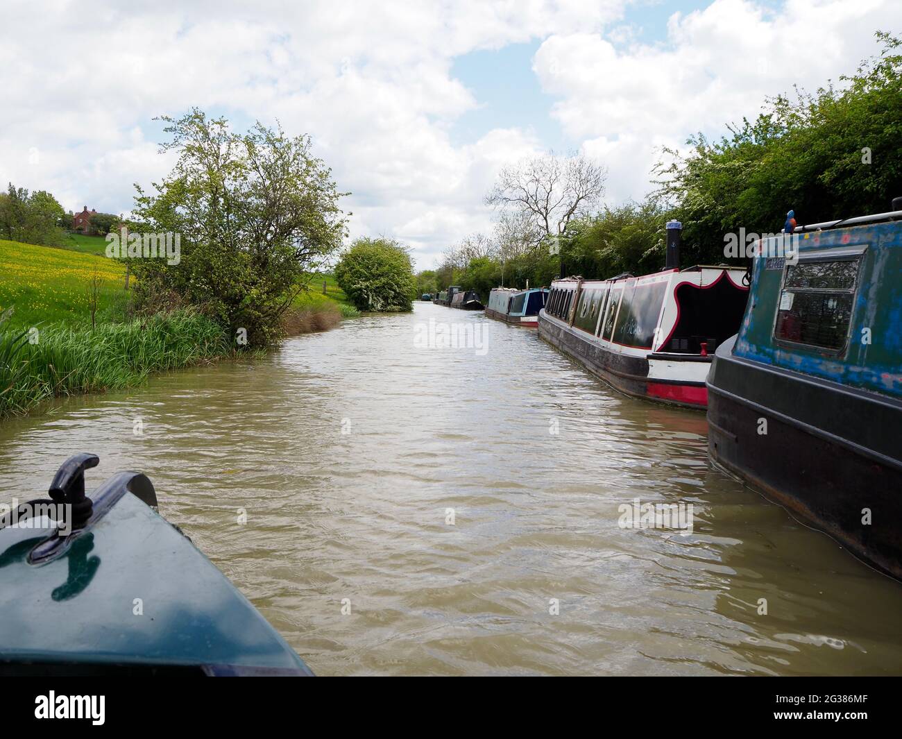 a line of moored narrowboats on the South Oxford canal seen from the bow of another boat Stock Photo