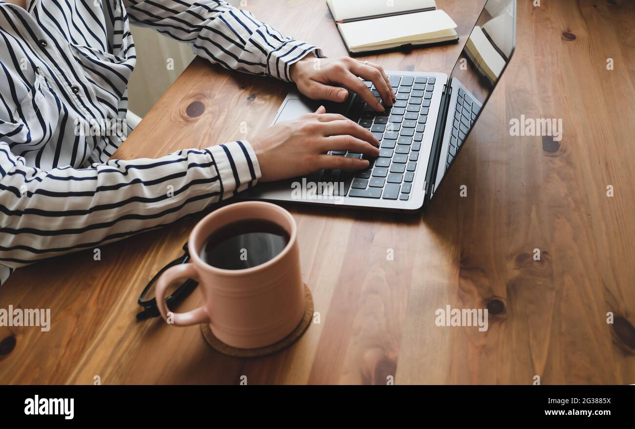 Young woman working at table with coffee, laptop and notepad. Stock Photo