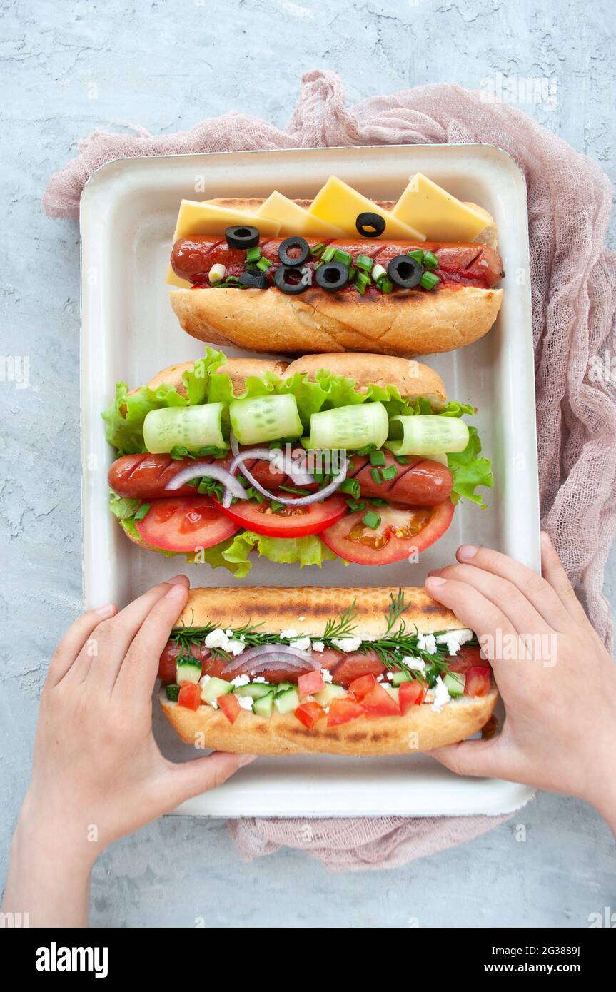 Child's hands holding a delicious freshly cooked hot dog. Stock Photo