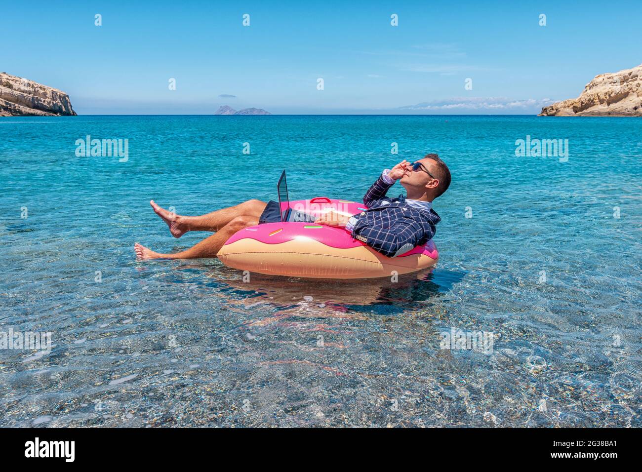 Businessman using laptop computer on an inflatable donut in the sea ...