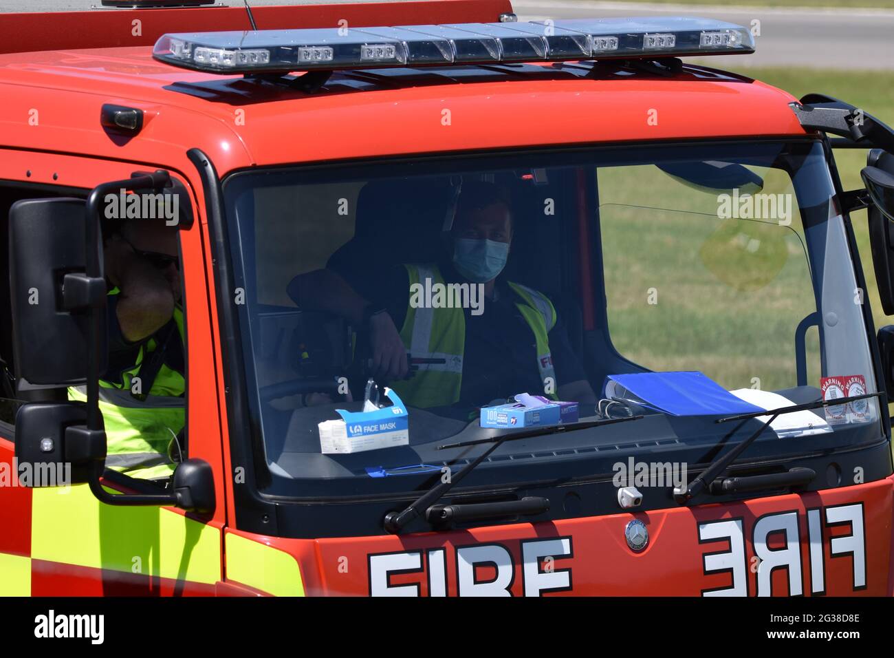 A fire engine at Bristol International Airport with two firemen inside with one wearing a face mask due to Covid-19 (Coronavirus) global pandemic Stock Photo