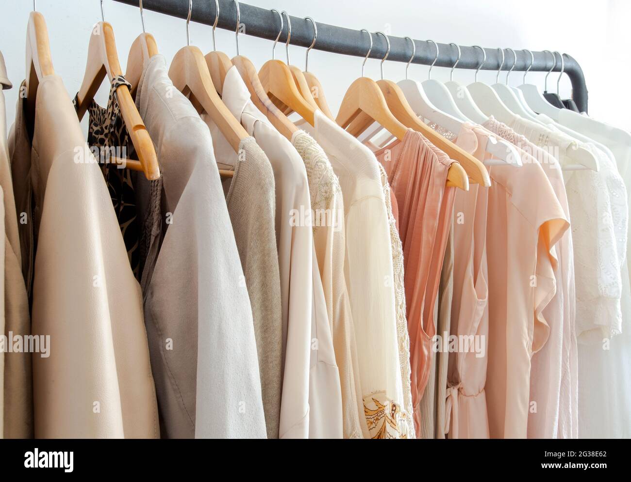 Stylish womans clothes hanging on a rack natural colors, trending concept, pastel colors in white room modern design closeup Stock Photo - Alamy