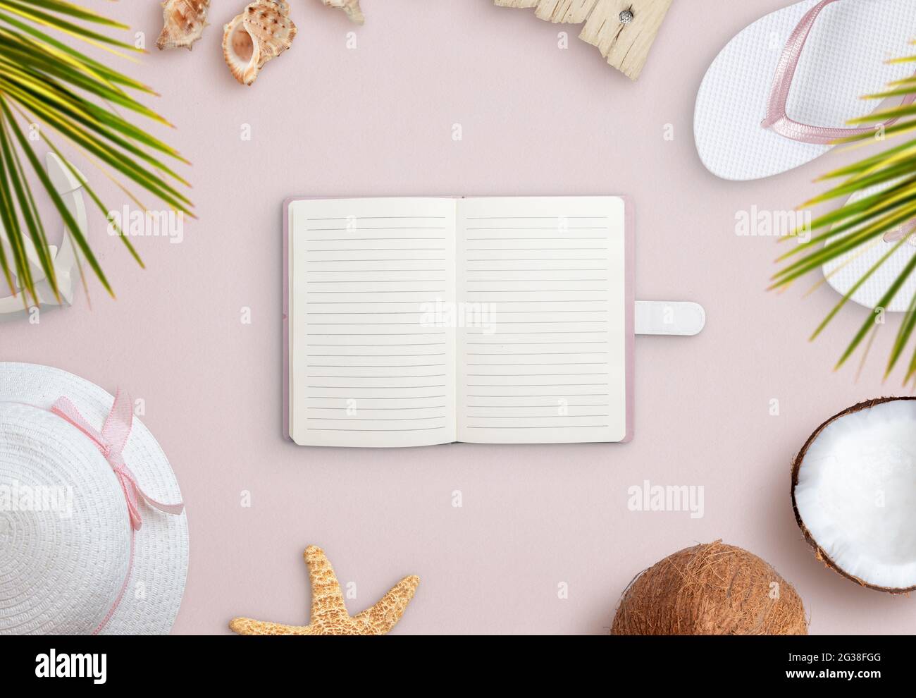 Notebook on beach surrounded by summer vacation accessories, shells and coconut. Empty notebook for text promotion Stock Photo