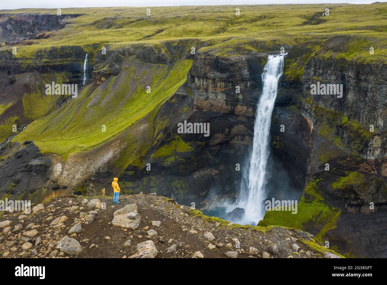 Aerial view of man standing on the cliff edge enjoying Iceland highland valley and Haifoss waterfall Stock Photo