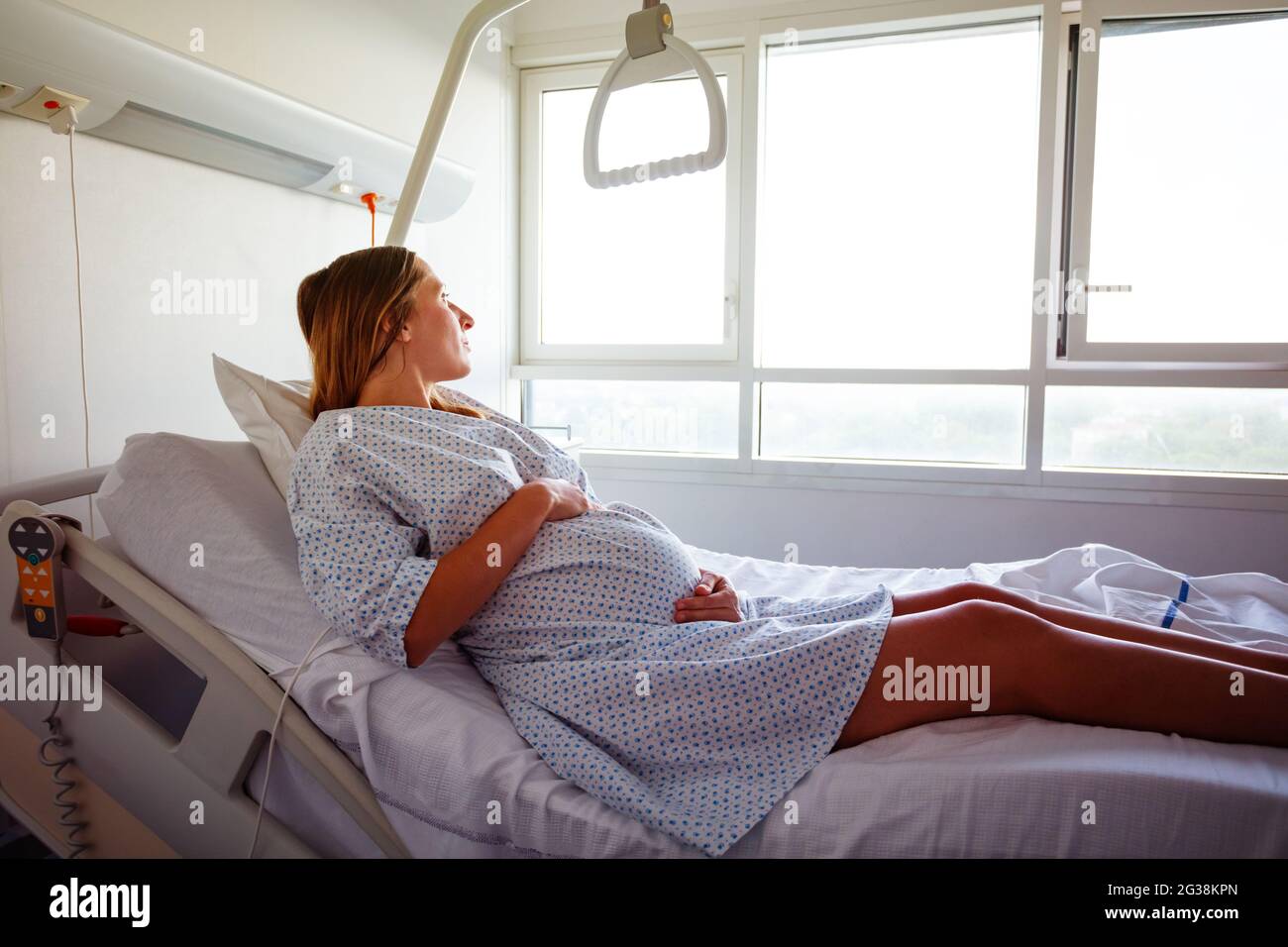 Pregnant woman laying in hospital bed hold belly Stock Photo