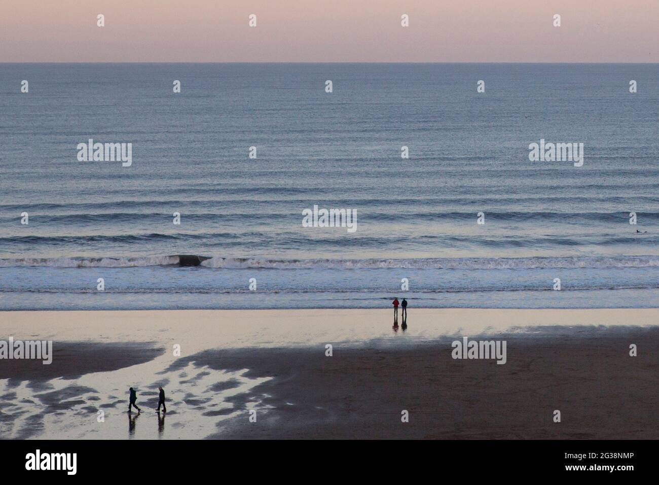 People walking along a beach in North England Stock Photo