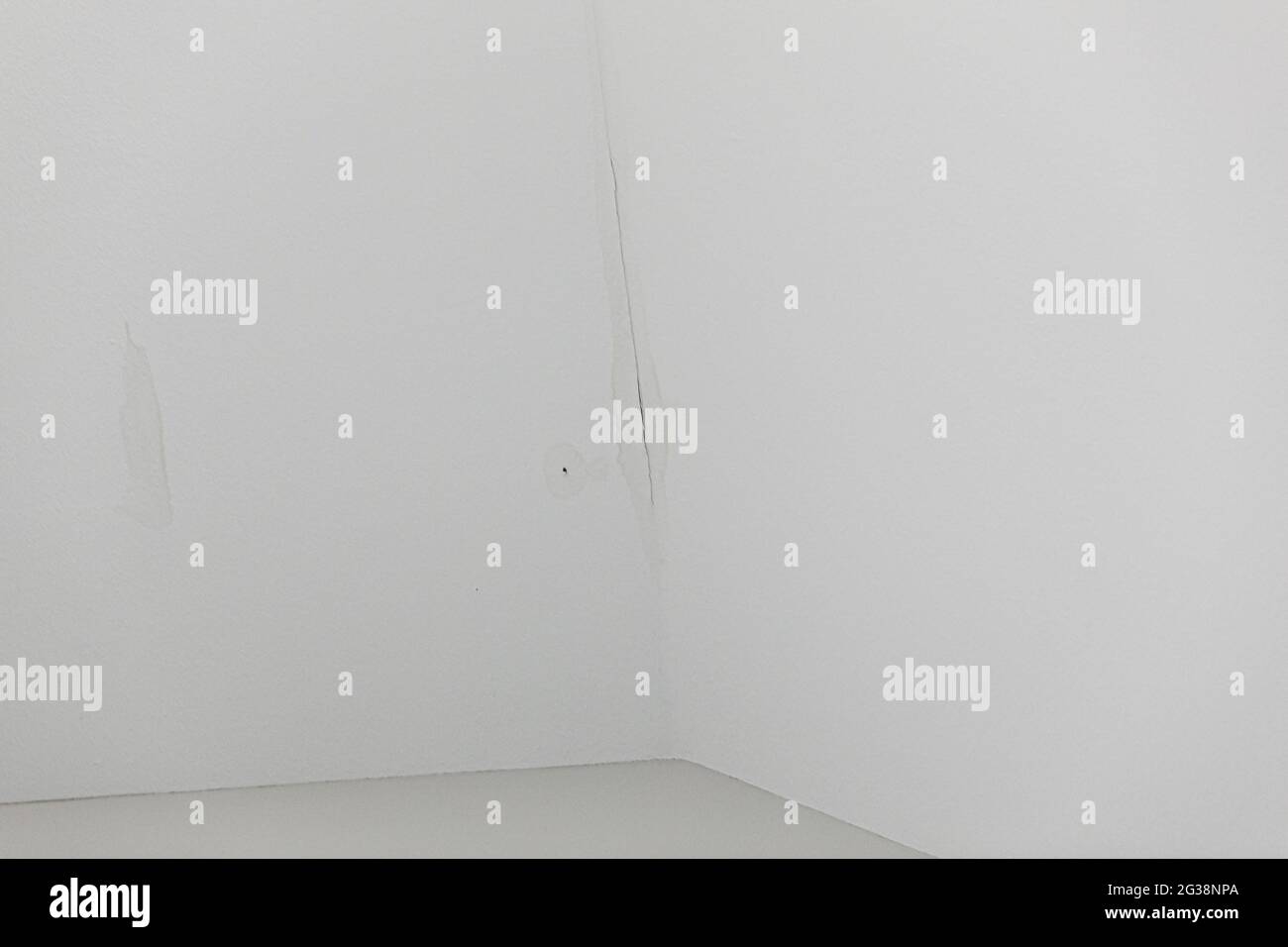 a small leak of water from the roof on an interior white ceiling Stock Photo