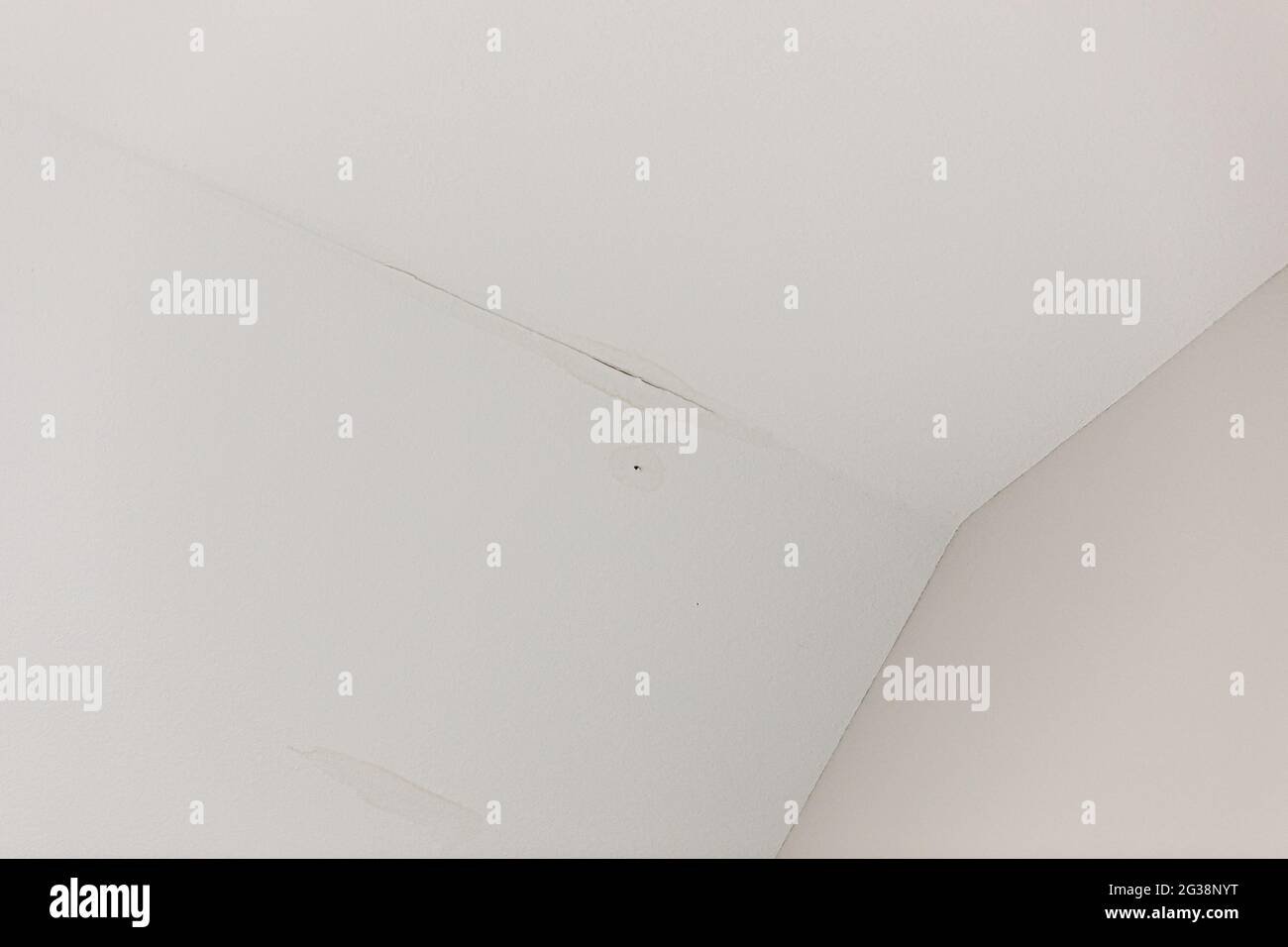 a small leak of water from the roof on an interior white ceiling Stock Photo