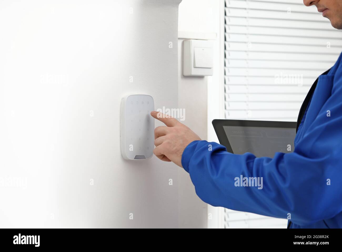 Worker with tablet computer checking alarm system indoors Stock Photo