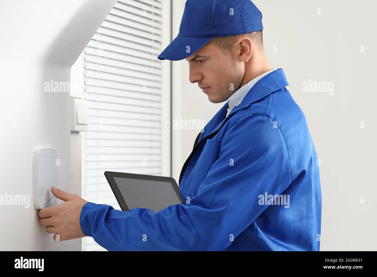 Worker with tablet computer checking alarm system indoors Stock Photo