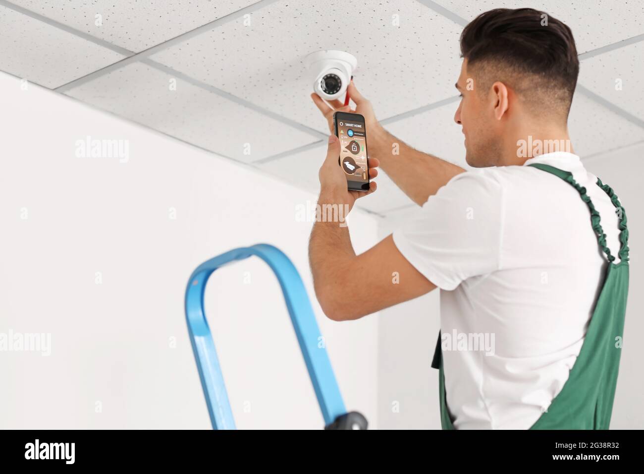 Worker with mobile phone checking alarm system indoors Stock Photo