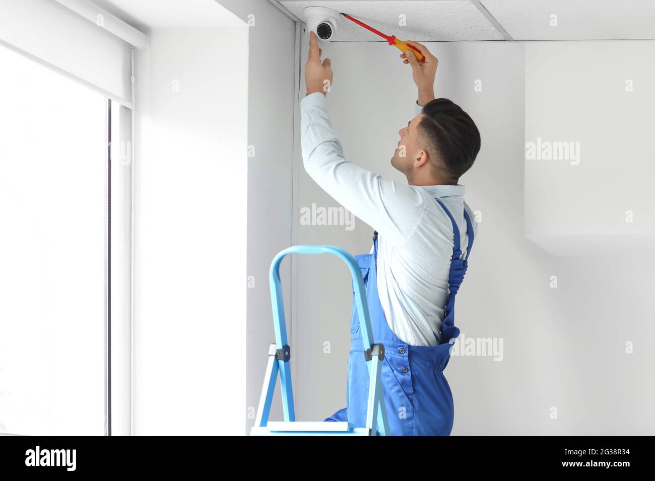 Worker installing CCTV camera in room Stock Photo