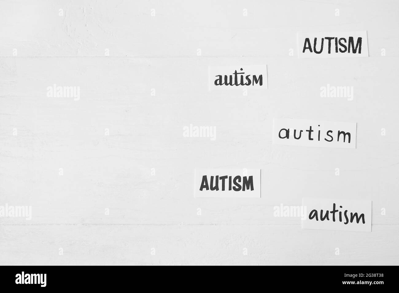 Pieces of paper with words AUTISM on white wooden background Stock Photo