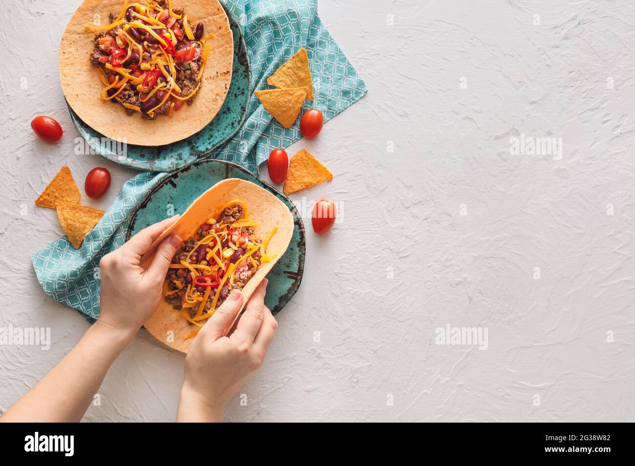Female hands with tasty tacos on light background Stock Photo