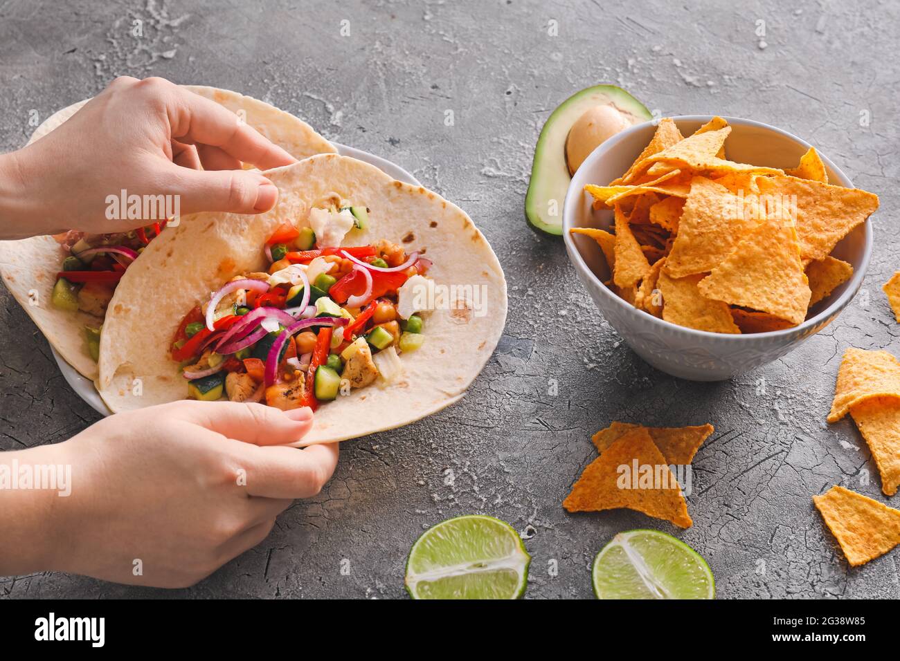Female hands with tasty tacos on grunge background Stock Photo