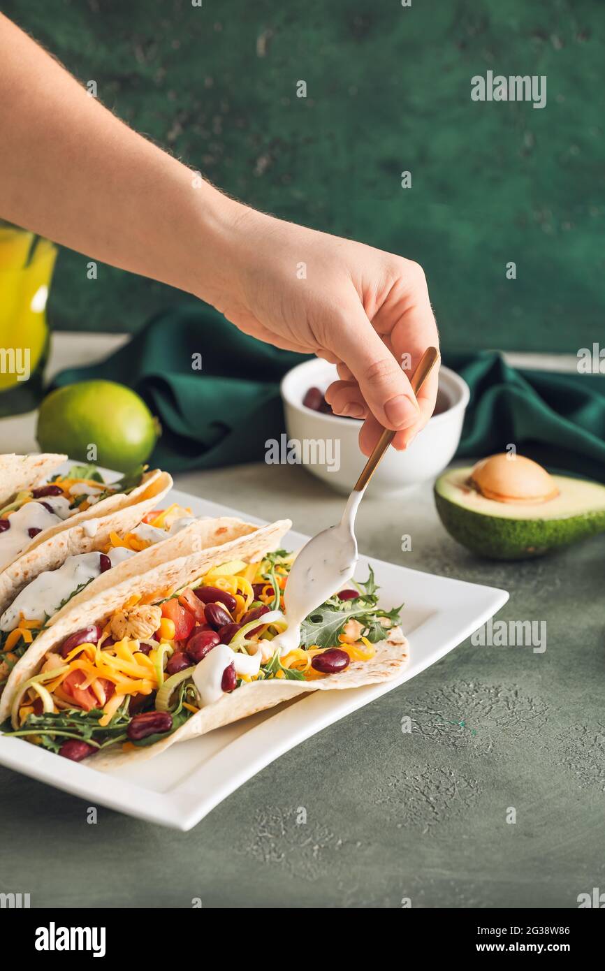 Woman cooking tasty tacos on color background Stock Photo