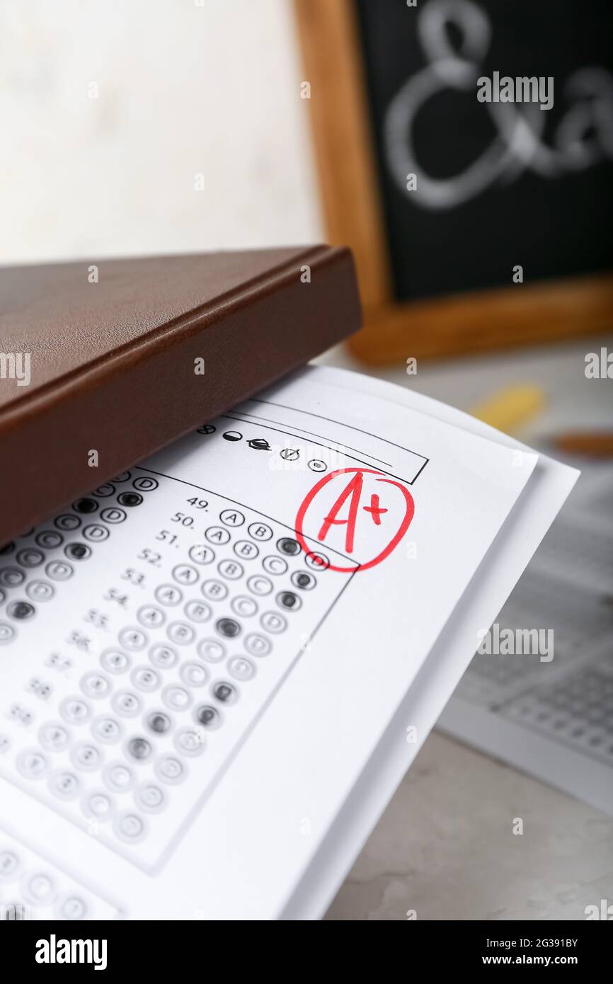 Book and checked answer sheet forms on table, closeup Stock Photo