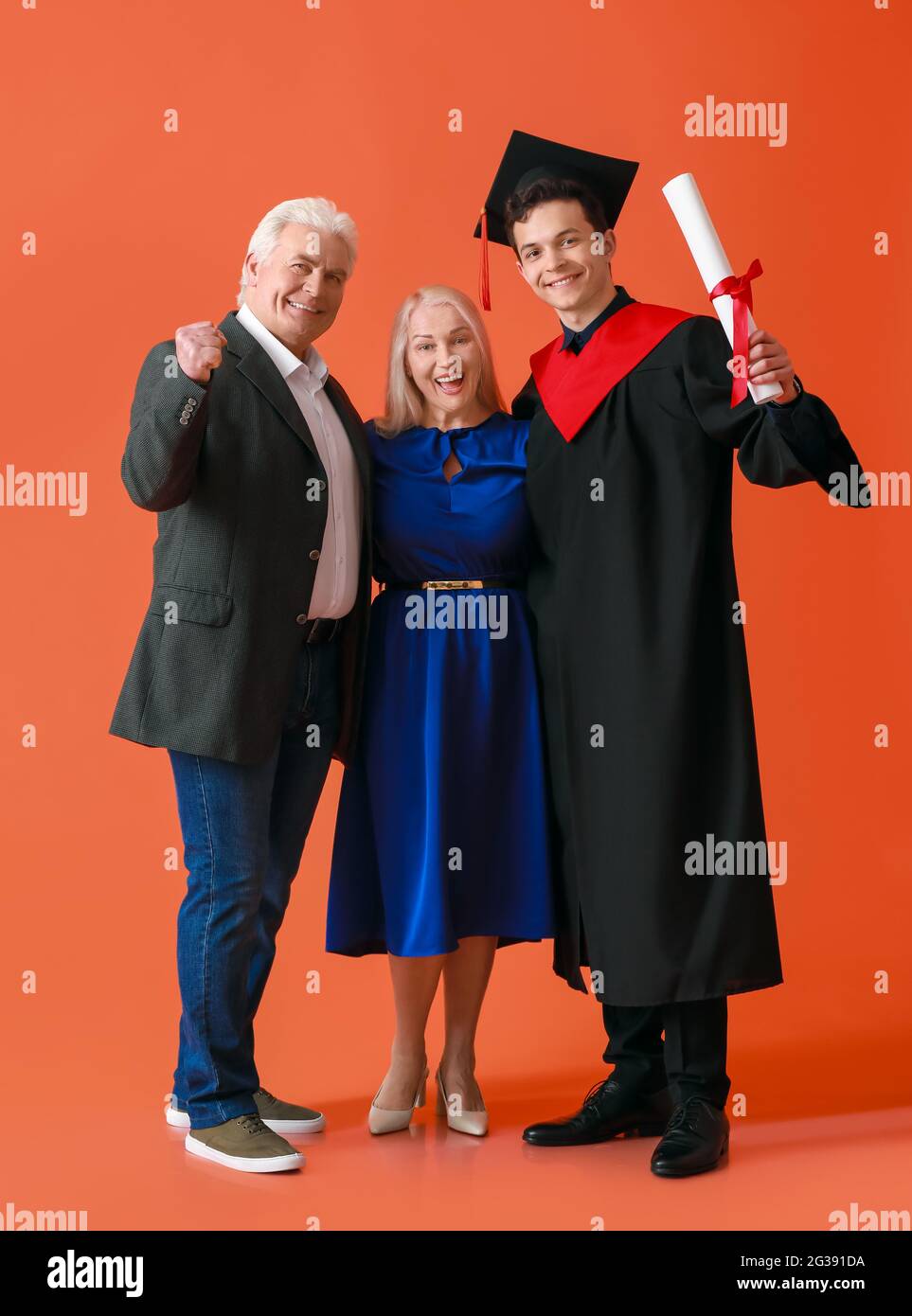 Happy male graduation student with his parents on color background ...