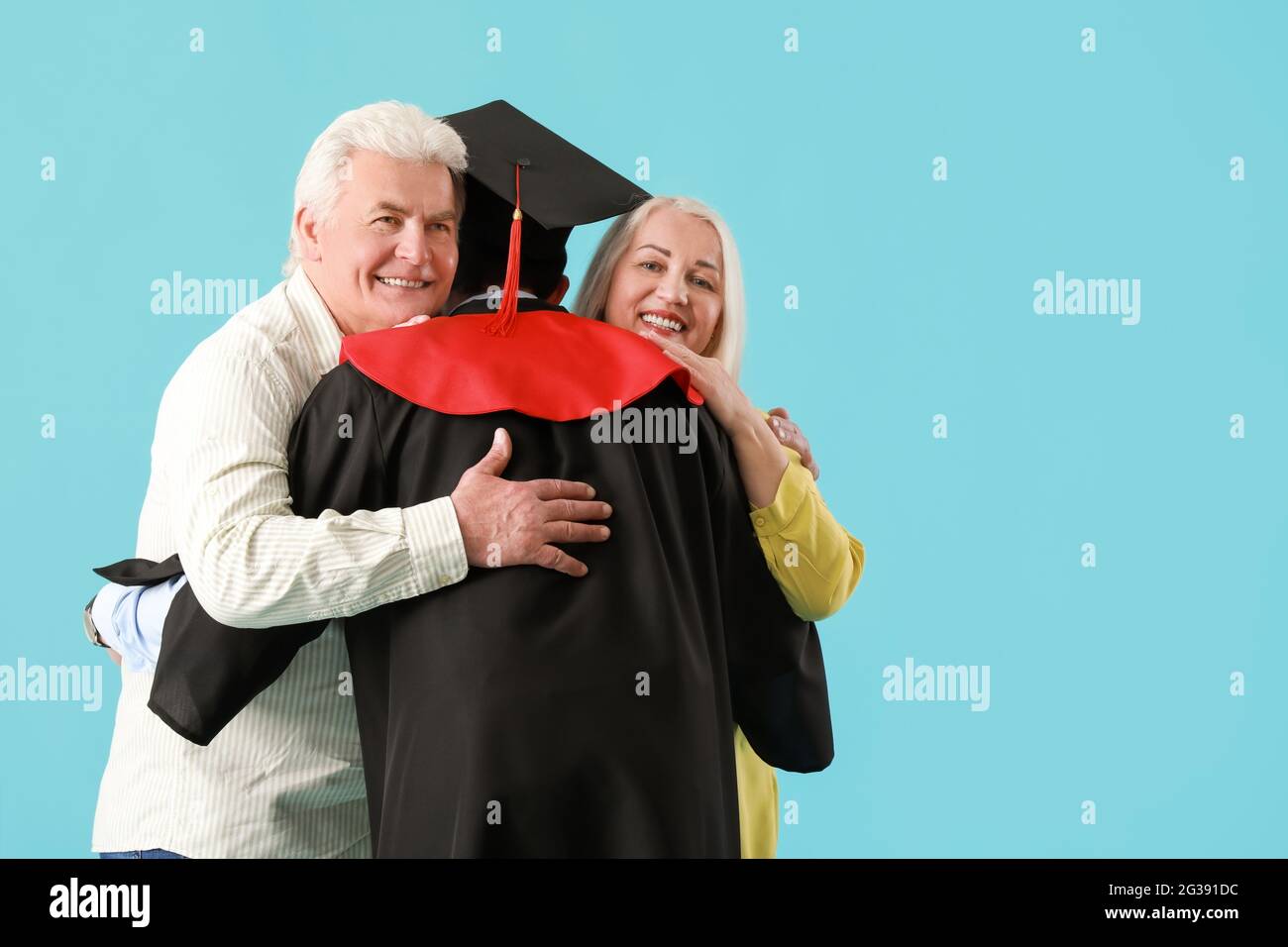 Happy male graduation student with his parents on color background ...