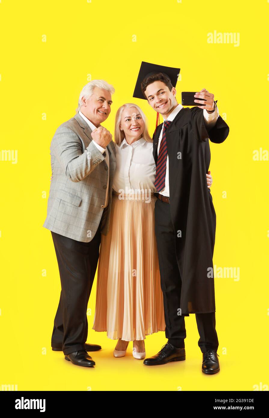 Happy male graduation student with his parents taking selfie on color ...
