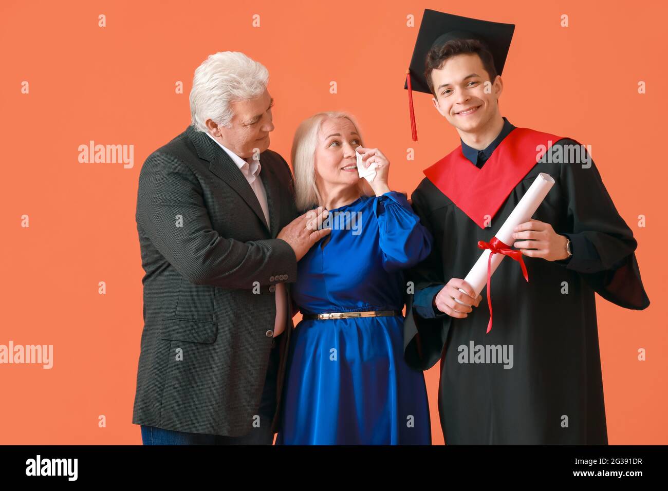 Happy male graduation student with his parents on color background ...