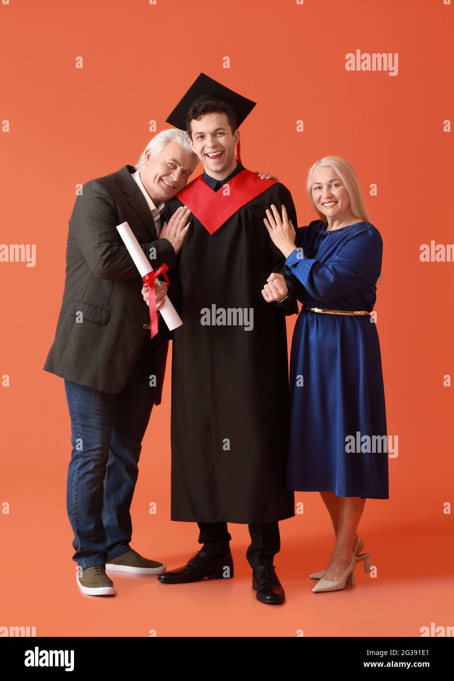 Happy male graduation student with his parents on color background ...