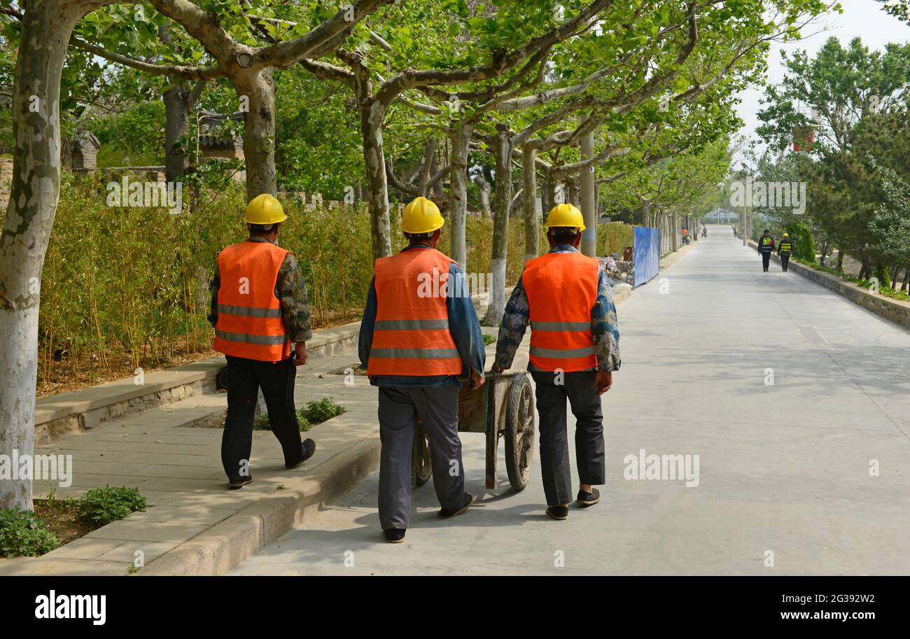 Workers walk along a path on Liugong Island off the coast of Weihai, China, during renovation work on the many historical buildings on the island. Stock Photo