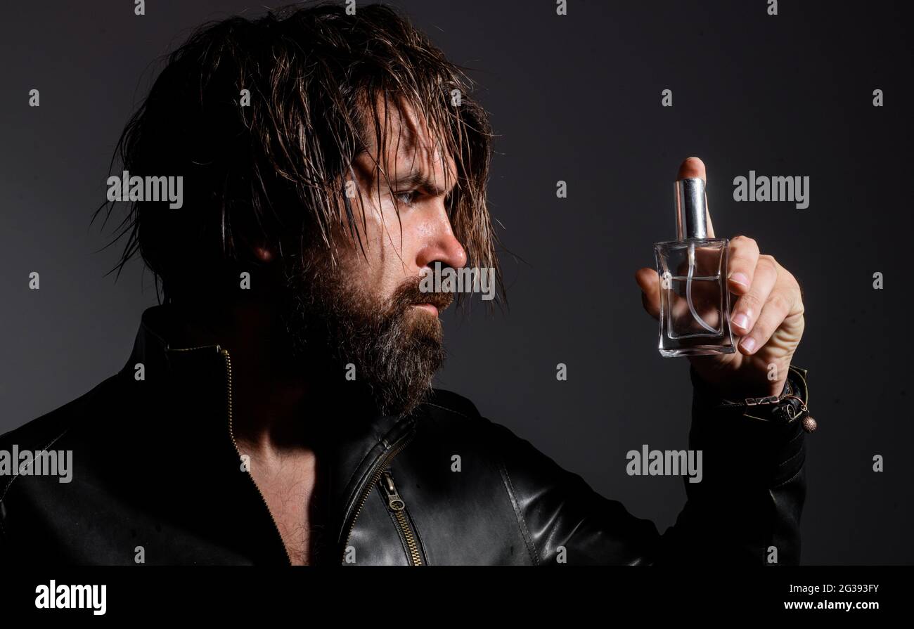 Bearded man in leather jacket with Bottle of perfume or cologne