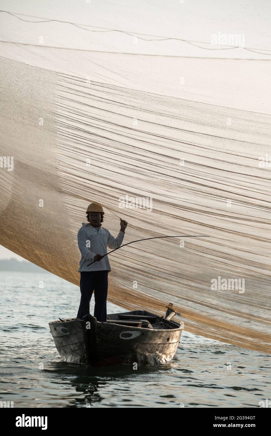 Fisherman tending his net, Thu Bon River, Hoi An, Vietnam Stock Photo