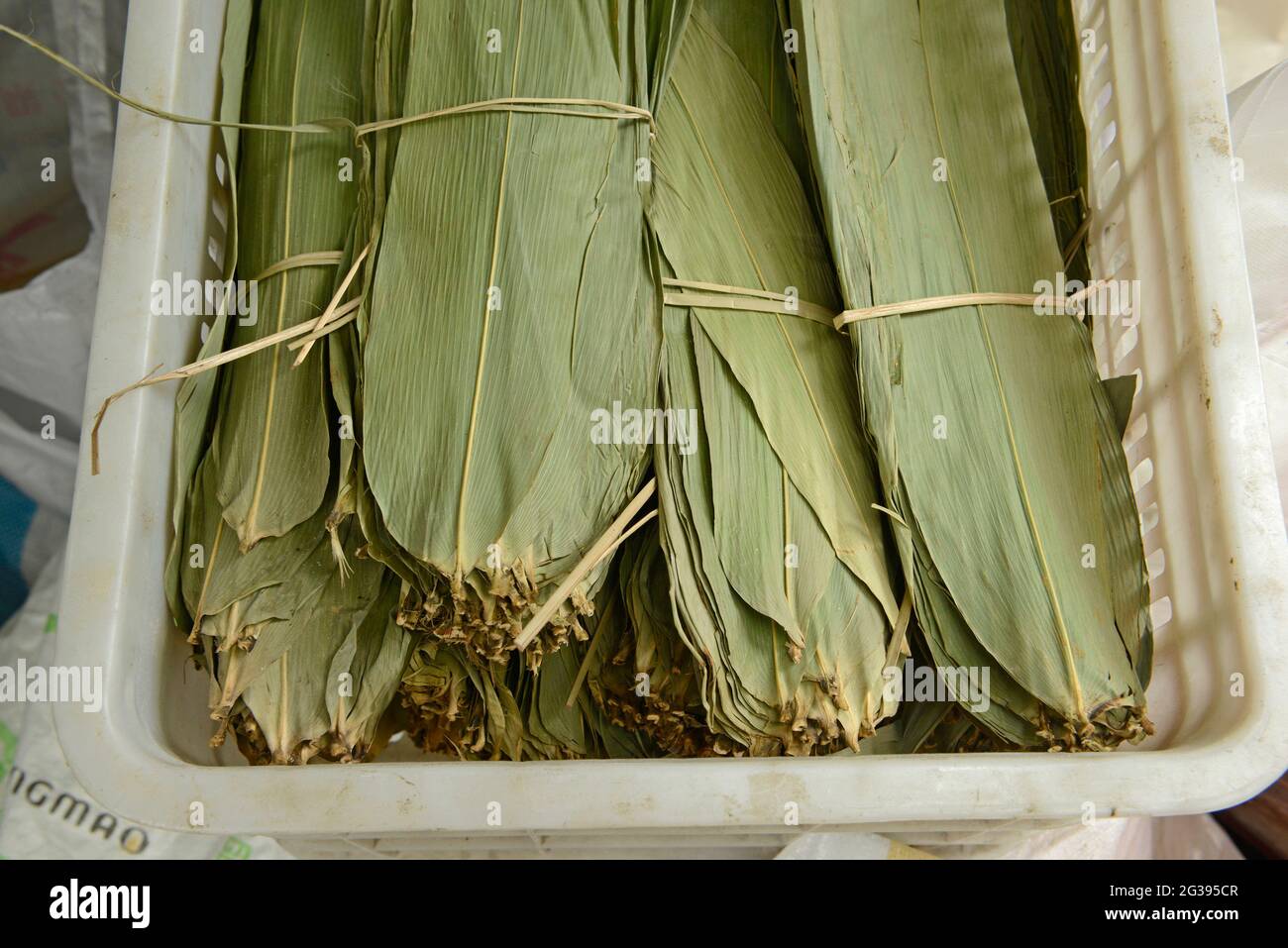 Bundles of dry Dendrocalamus bamboo leaves on sale at a food products market in Yantai, Shandong province, China, to be used to wrap Zongzi dumplings. Stock Photo