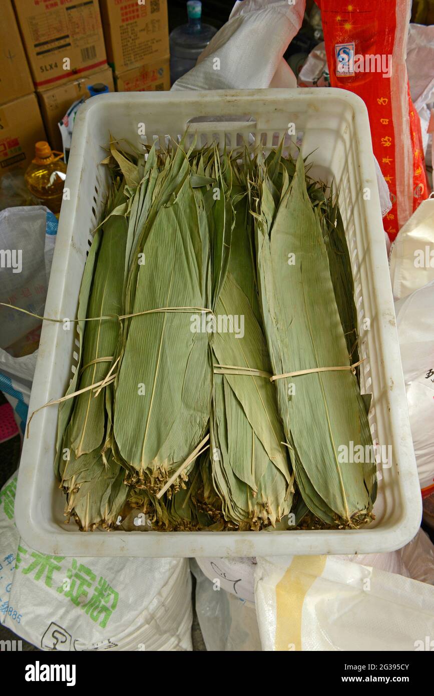 Bundles of dry Dendrocalamus bamboo leaves on sale at a food products market in Yantai, Shandong province, China, to be used to wrap Zongzi dumplings. Stock Photo