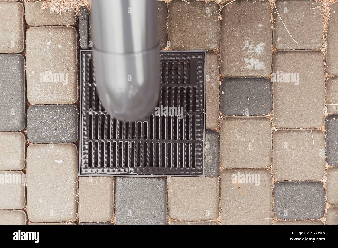 stormwater pipe on facade with rainwater drainage into drainage system with  a sewer manhole grill Stock Photo - Alamy