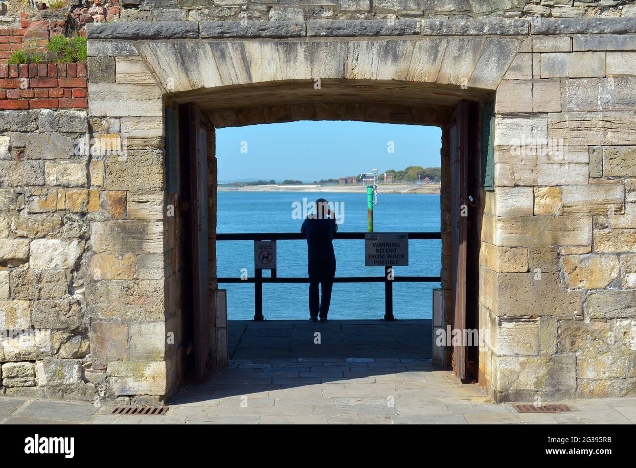A man stands looking out to sea, with his hand on his face it gives a sense of thinking or pondering. Stock Photo
