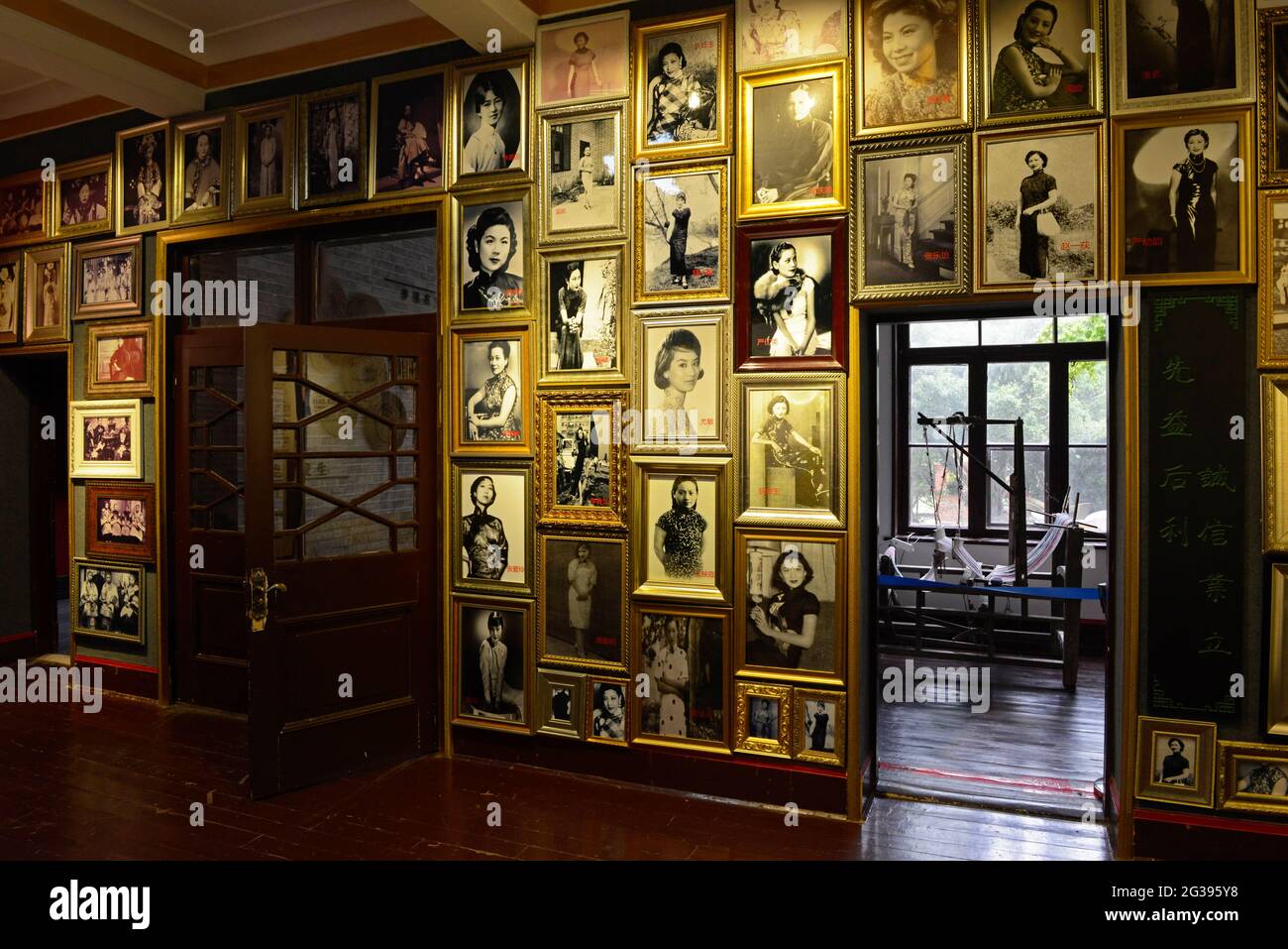 Photos of famous Chinese women in years past all wearing the Qipao dress line the walls at the Qipao museum in an old house in Yantai, China Stock Photo